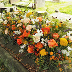 A Casket Spray full o warm sunset colours, placed on a grave